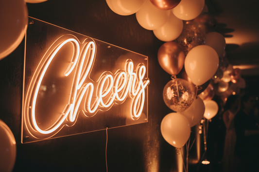 Glowing neon cursive lettering sign at an event with balloon decorations
